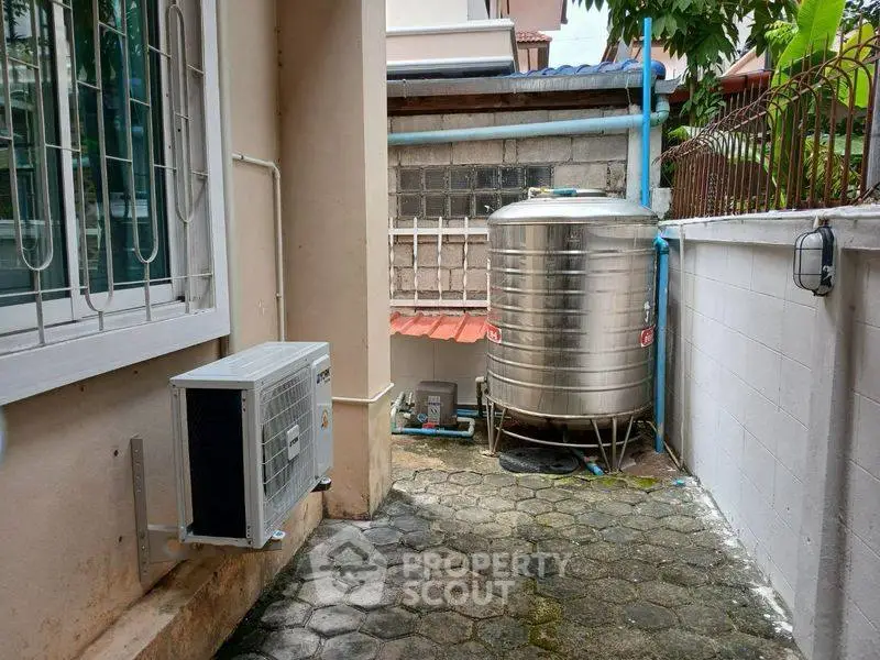 Outdoor area with water tank and air conditioning unit in residential property.