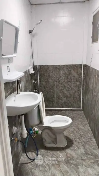 Compact bathroom with tiled walls and floor, featuring a shower and toilet.