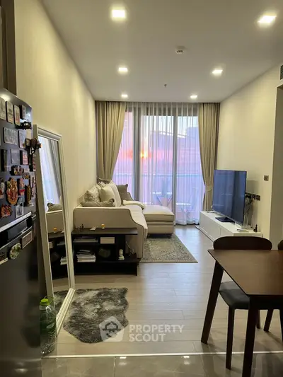Modern living room with cozy decor and large window view at sunset.