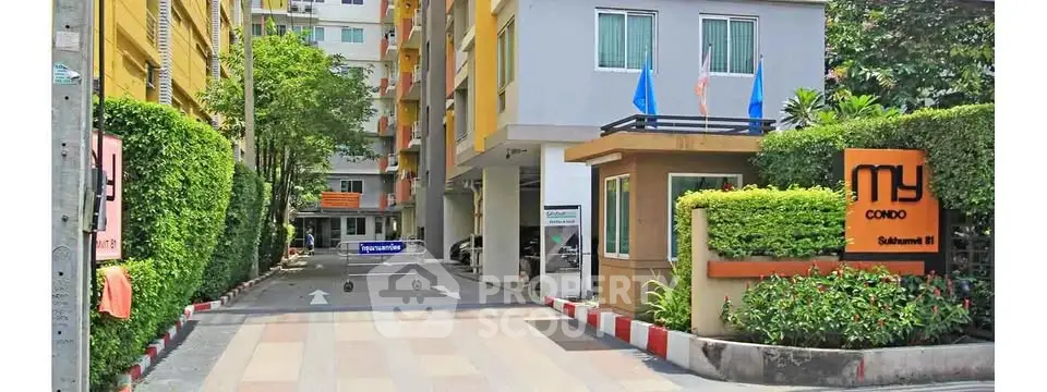 Modern condo entrance with lush greenery and secure gated access in vibrant urban setting.