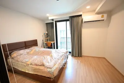 Spacious bedroom with modern decor and balcony access in a stylish apartment.