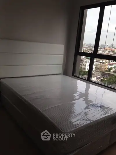 Spacious bedroom with large window offering city views, featuring a new mattress and modern headboard.