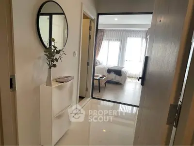 Modern apartment entrance with sleek hallway leading to a cozy living room with natural light.