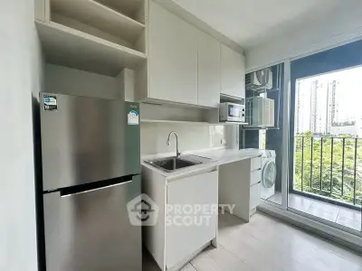 Modern kitchen with stainless steel fridge and balcony view in urban apartment.