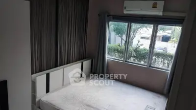 Cozy bedroom with large window and air conditioning, offering a serene view of greenery outside.