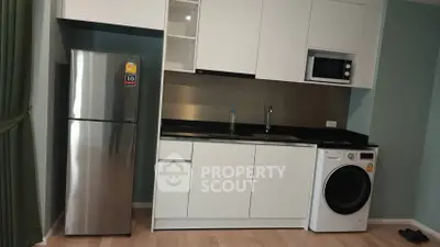 Modern kitchen with sleek appliances including fridge, microwave, and washing machine in stylish apartment.