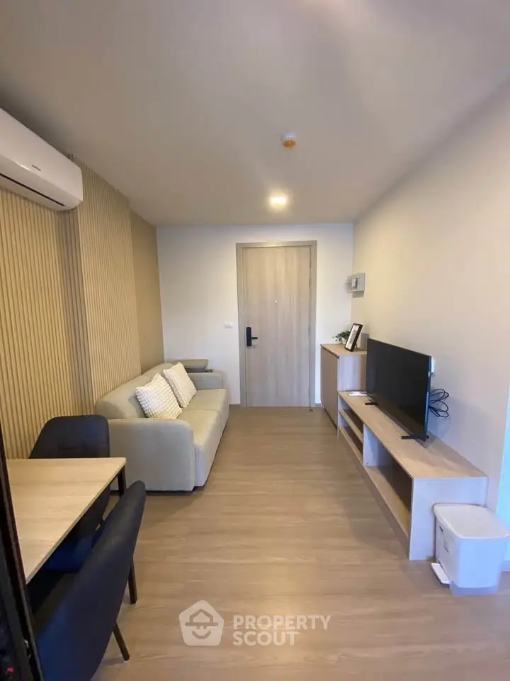 Modern living room with sleek furniture and neutral tones, featuring a cozy sofa and flat-screen TV.
