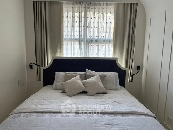 Cozy bedroom with elegant headboard and soft lighting, perfect for relaxation.