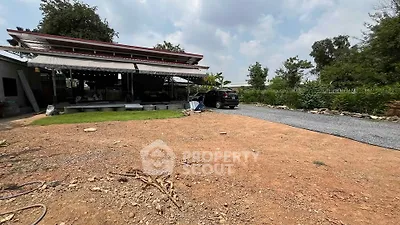 Spacious outdoor area with gravel driveway and covered patio, ideal for versatile use.