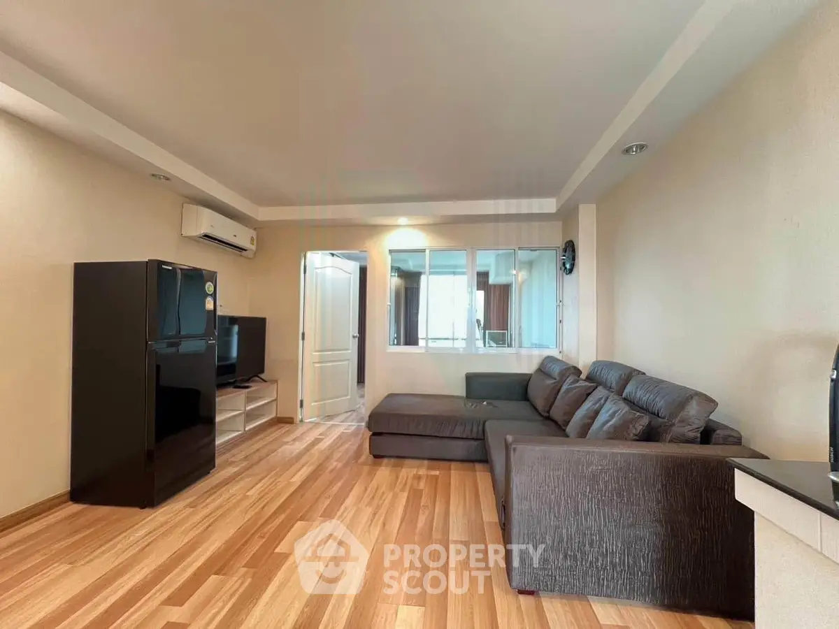 Spacious living room with modern sofa and wooden flooring in a cozy apartment.