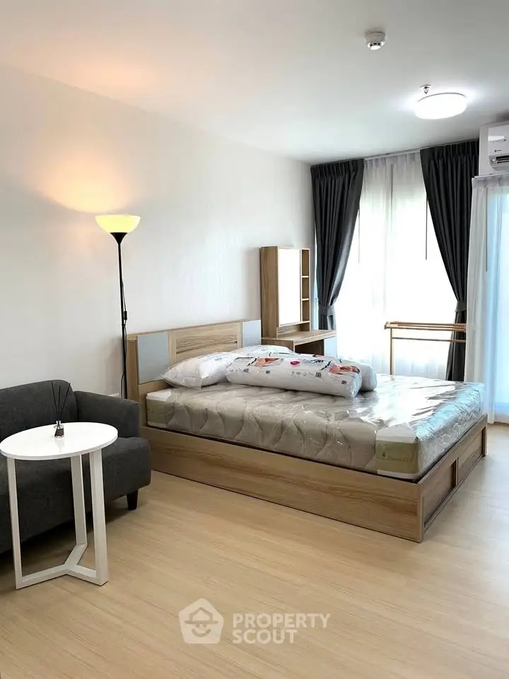 Modern bedroom with cozy bed, stylish furniture, and natural light from large windows.