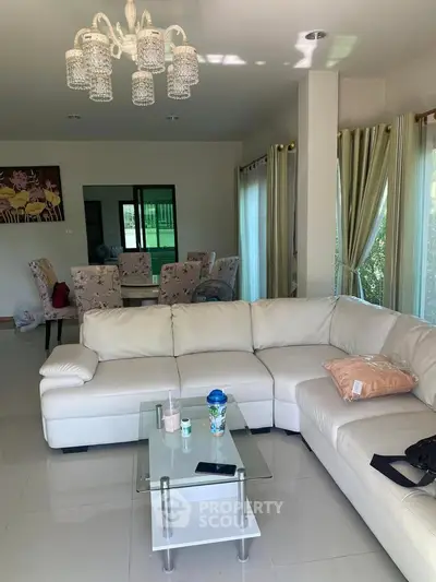 Spacious living room with elegant chandelier and modern furniture in a bright, airy home.