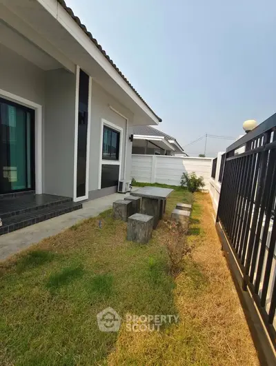 Charming modern home exterior with lush garden and stylish patio seating.