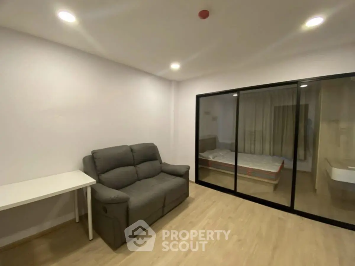 Modern living room with sofa and glass partition to bedroom