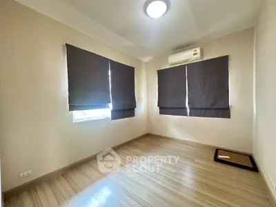 Spacious empty bedroom with wooden flooring and air conditioning, ready for customization.