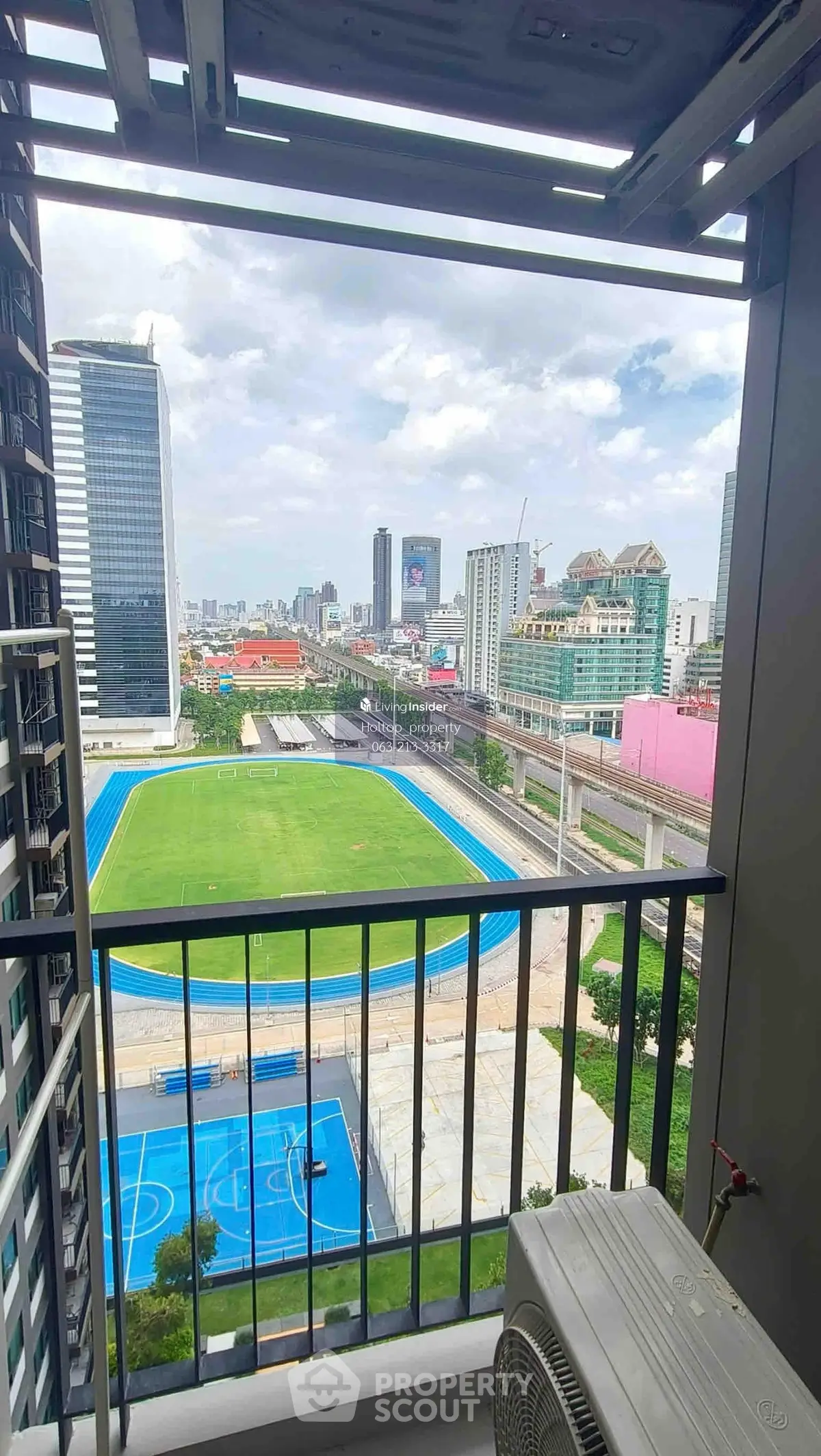 Stunning cityscape view from a high-rise balcony overlooking sports fields and urban skyline.