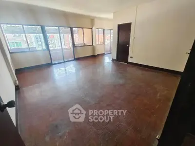 Spacious empty room with large windows and wooden flooring, ideal for customization.