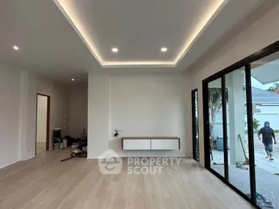 Spacious modern living room with sleek flooring and large glass doors opening to a patio.