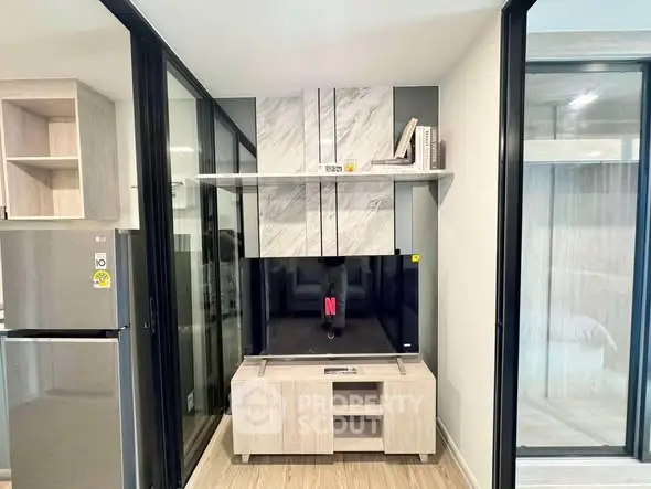 Modern living room with sleek TV unit and sliding glass doors in stylish apartment.