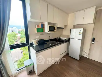 Modern kitchen with sleek cabinets and appliances, offering a bright view from the window.