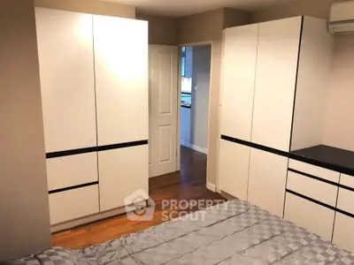 Modern bedroom with sleek white wardrobes and cozy bedding