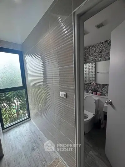 Modern bathroom with textured wall tiles and frosted glass window for privacy.