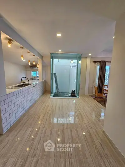 Spacious open-plan kitchen and dining area with modern lighting and sleek flooring.