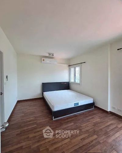 Spacious bedroom with wooden flooring and modern air conditioning unit.