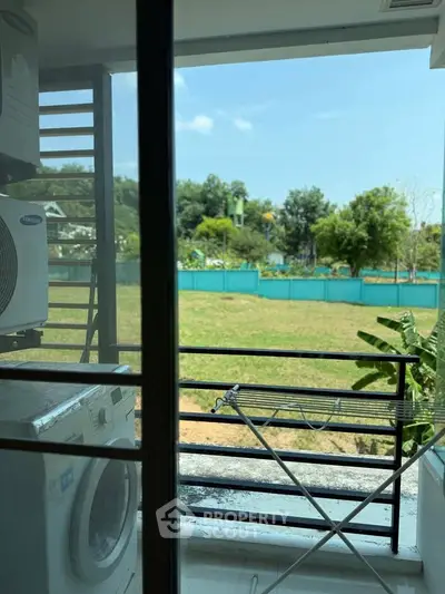Charming balcony view with lush greenery, featuring a washing machine and drying rack for convenience.