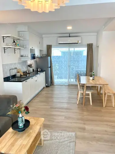 Modern open-plan living room with kitchen and dining area, featuring wooden flooring and stylish decor.