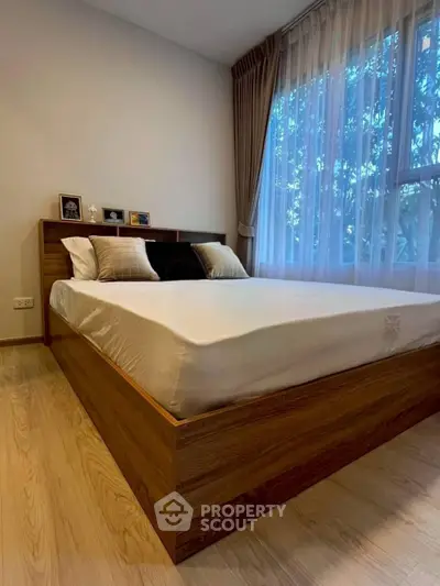 Modern bedroom with wooden bed frame and large window with curtains, offering a cozy and inviting atmosphere.