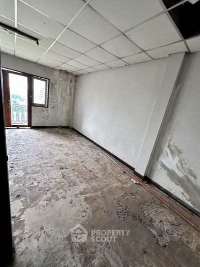 Spacious room with potential for renovation, featuring large window and balcony access.
