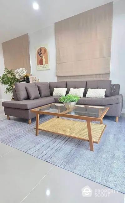 Stylish living room with modern gray sofa and glass coffee table on elegant rug.