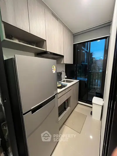 Modern compact kitchen with sleek appliances and large window view