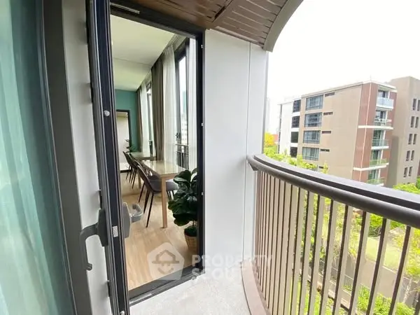 Modern apartment balcony with view of dining area and cityscape.