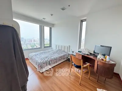 Spacious bedroom with city view, featuring a cozy bed and a work desk, perfect for urban living.