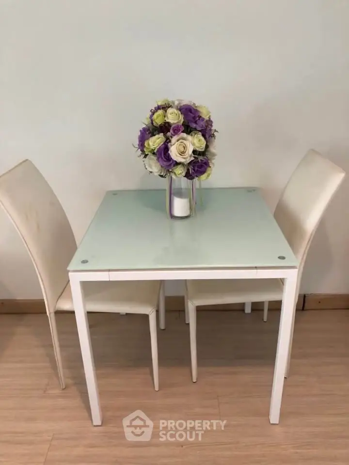 Charming dining setup with elegant glass table and floral centerpiece, perfect for cozy meals.