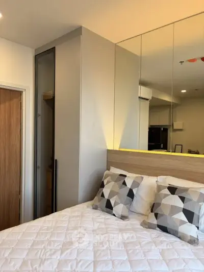 Modern bedroom with stylish decor and mirrored wardrobe in a cozy apartment.