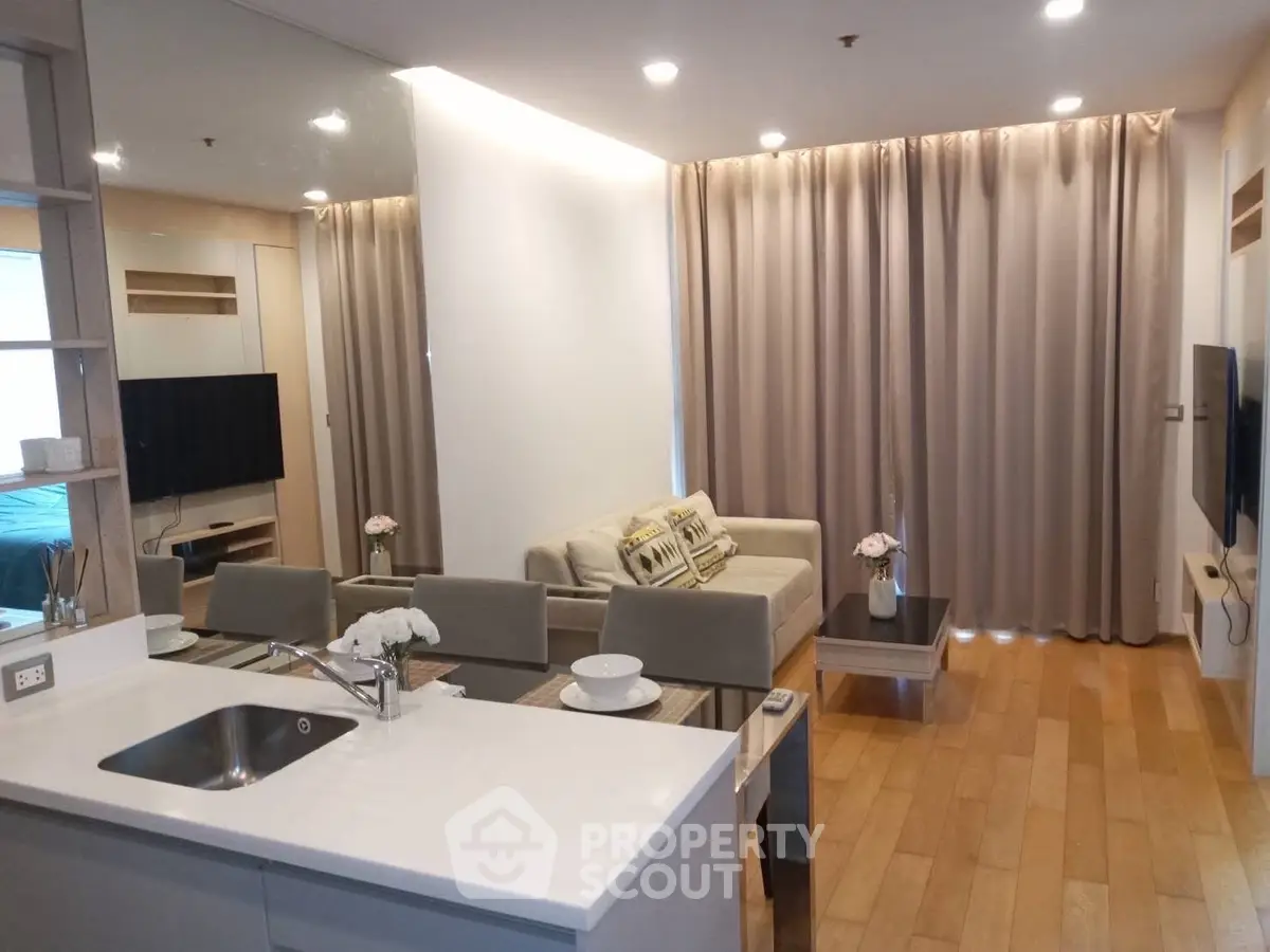 Modern living room with open kitchen, sleek design, and cozy ambiance in a stylish apartment.
