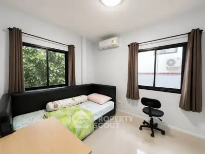 Cozy bedroom with modern furnishings and large windows offering natural light.