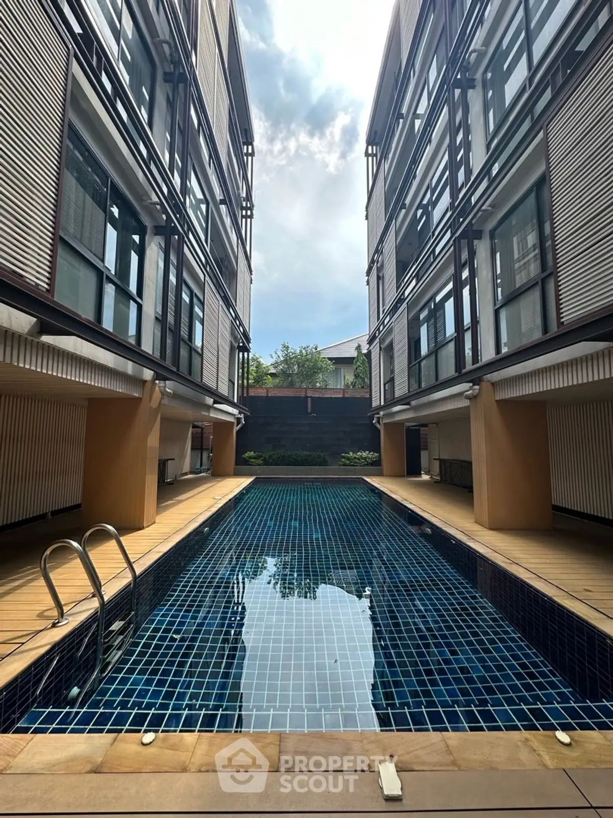 Modern apartment complex with a sleek swimming pool and contemporary architecture.