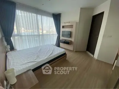 Modern bedroom with large window and stylish decor in a high-rise apartment.