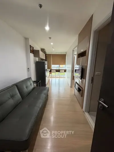 Modern apartment interior with sleek living room and kitchen area, featuring stylish furniture and natural lighting.