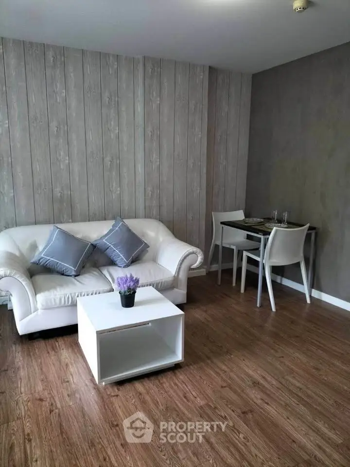 Modern living room with stylish sofa and dining area, featuring elegant wooden flooring.