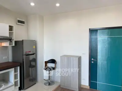 Modern kitchen with sleek fridge and stylish bar stool in a contemporary apartment.
