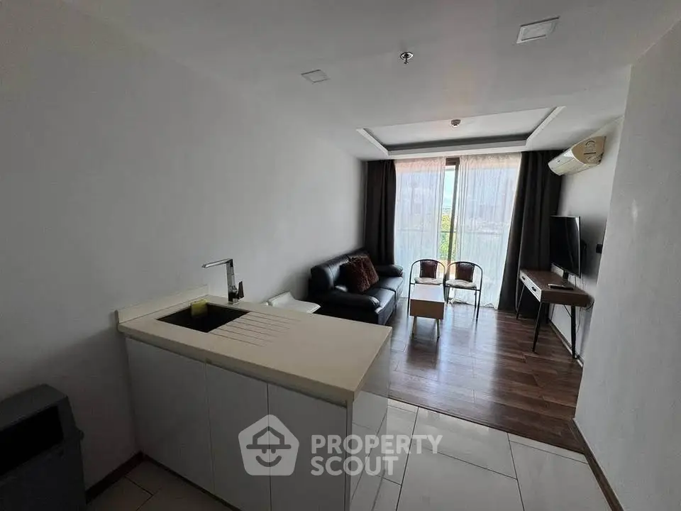 Modern living room with open kitchen and balcony view in stylish apartment.