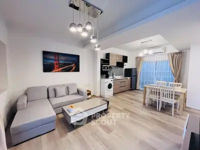 Modern open-plan living room with kitchen, featuring stylish decor and natural light.