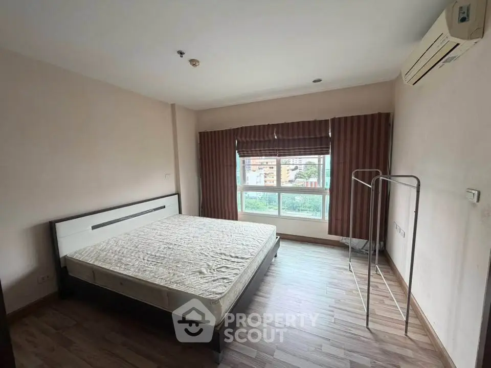 Spacious bedroom with large window and air conditioning in modern apartment.