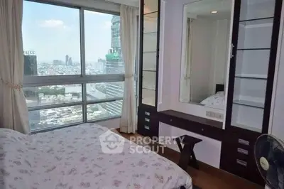 Spacious bedroom with large window offering stunning city views, featuring built-in storage and elegant decor.