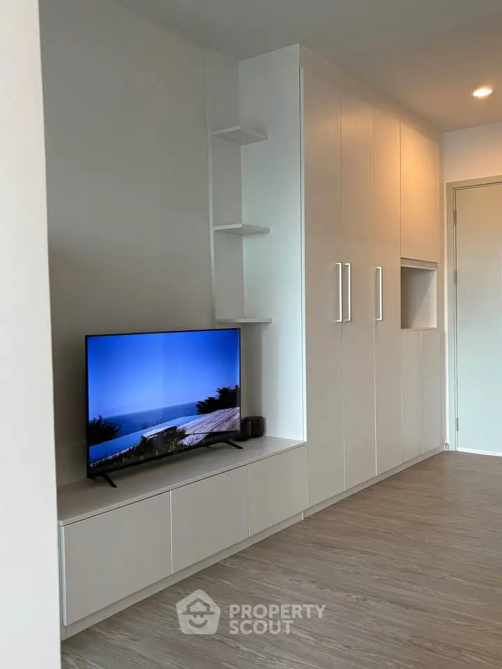 Modern living room with sleek built-in storage and flat-screen TV, showcasing minimalist design and functionality.
